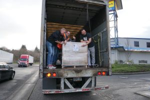 Toilet Paper Drive Brad and John standing in Truck with A pallet of donations