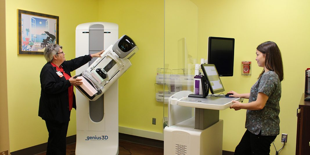 Terry J. and Jennifer F. adjust the angle on the Hologics Genius 3D Mammography imaging equipment