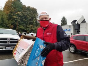 senior citizen in mask holding box of documents to shred for the BECU shred event