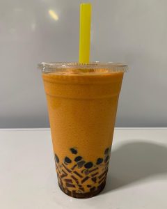 thai milk tea with boba and a yellow straw
