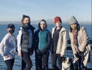 a group of One Community One Family volunteers standing at the beach with a dog