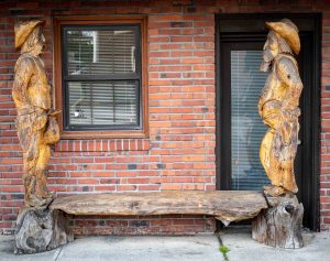 cedar carvings of a sheriff and an outlaw on either side of a bench in Sedro-Woolley