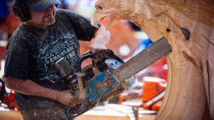 man carving a design out of wood with a chainsaw at Loggerodeo, July Fourth weekend