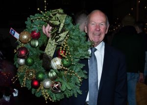 a man in a suit holding a Christmas wreath of fresh greens