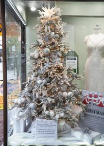 a flocked Christmas Tree decorated in white in a store window