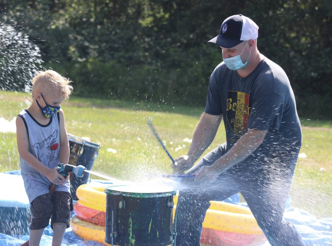 a man and a kid playing in a water sprinkler at Camp Korey