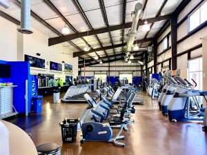 a large fitness room with rows of different types of fitness bikes, treadmills, etc.