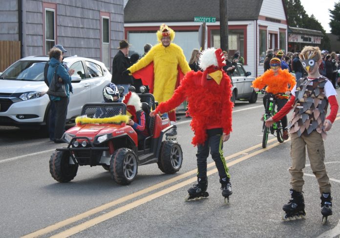 people in chicken costumes going down the street in Edison with a small battery-operated car