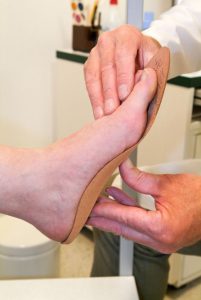 doctor fitting a foot with an orthotic