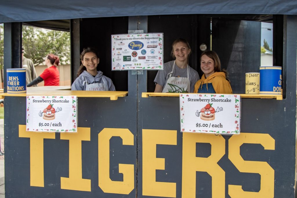 Wooden booth with three workers in it with yellow writing that says, 'Tigers.'