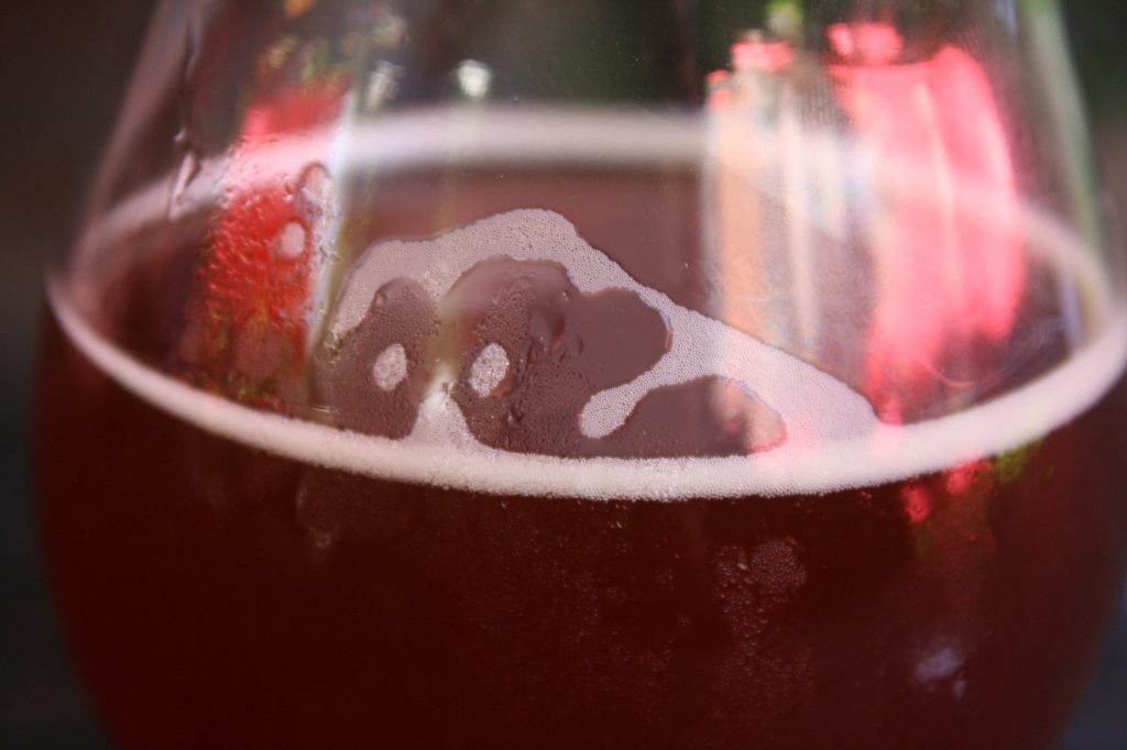 up close photo of a foaming red beer in a glass