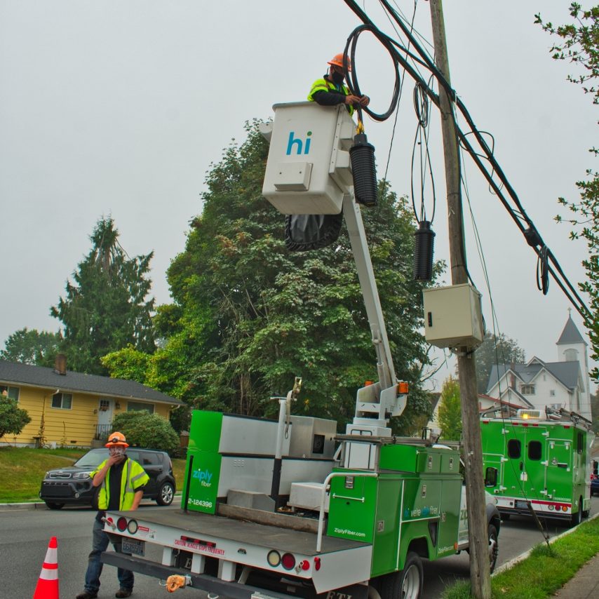 Green Ziply fiber trucks with work crew up in the baskets and on the ground