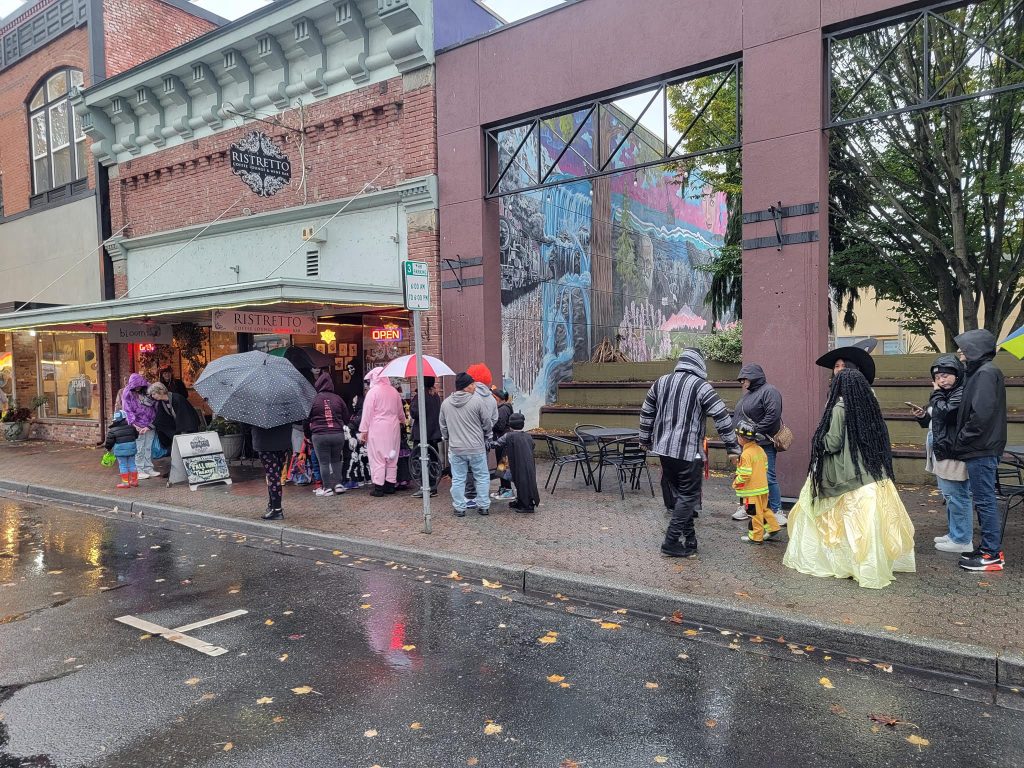 a line of people with umbrellas trick-or-treats in Mount Vernon