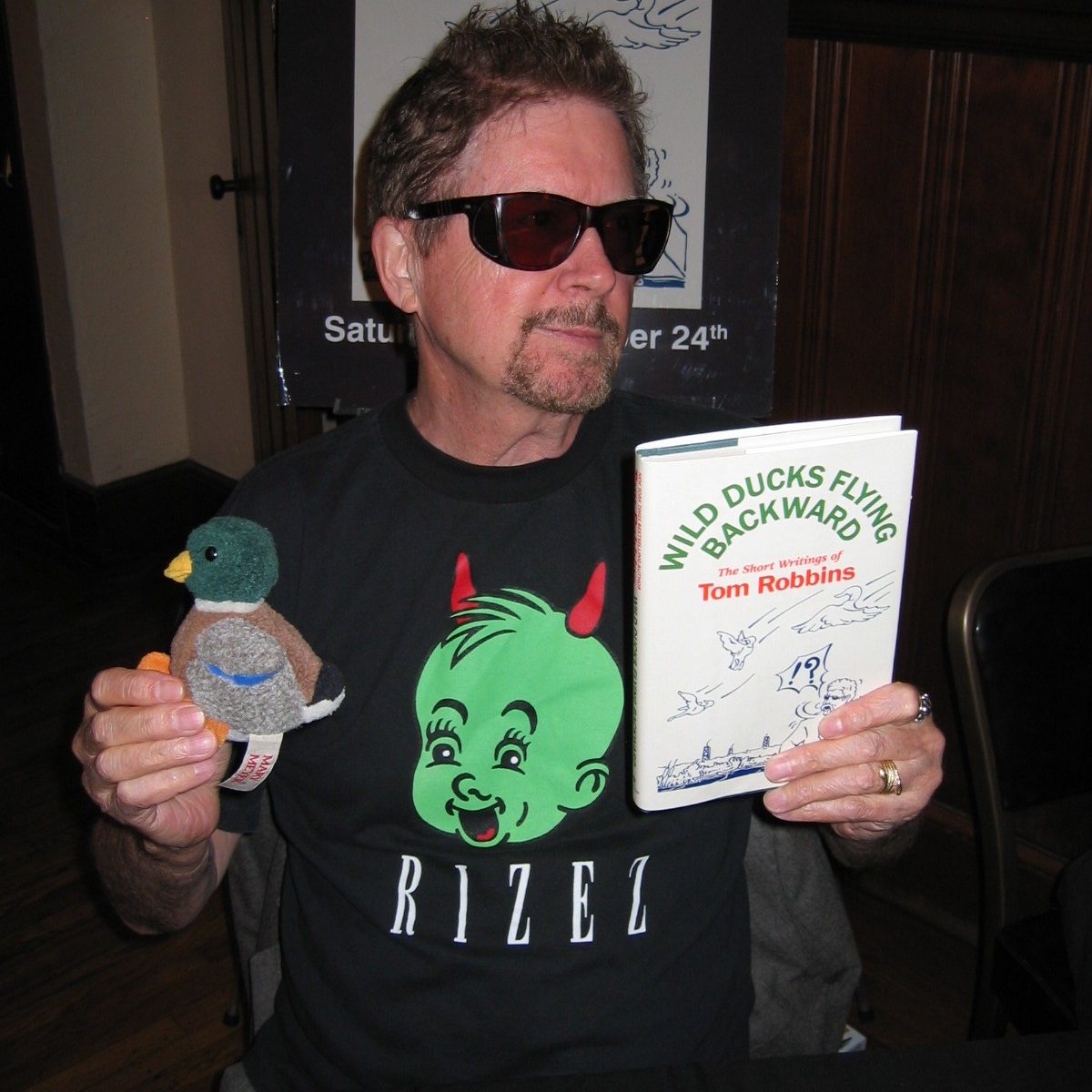 Tom Robbins holding up his book and a stuffed duck