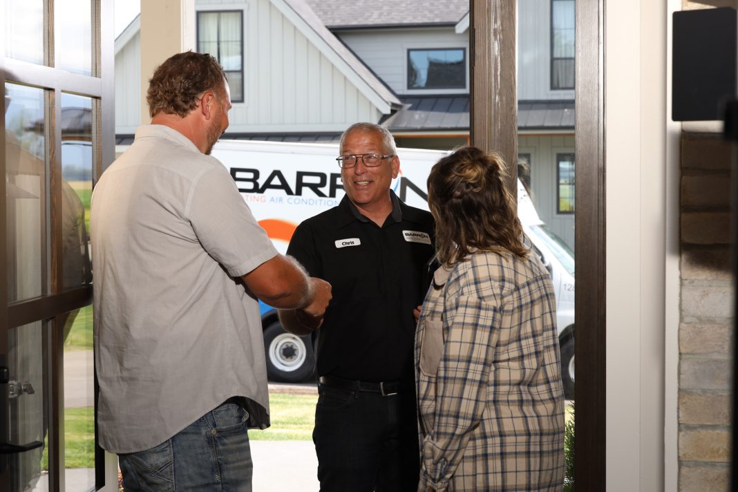 a Barron Heating tech shaking hands with a man who is standing with a woman at their front door