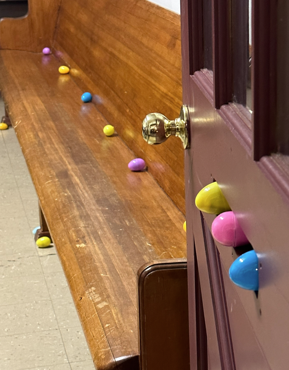 colored plastic eggs hidden in a door, on the floor and on a wooden bench