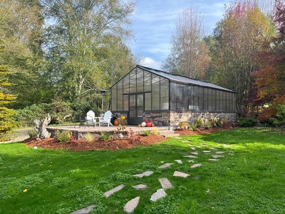 a greenhouse with a grass lawn in front of it and a brick patio