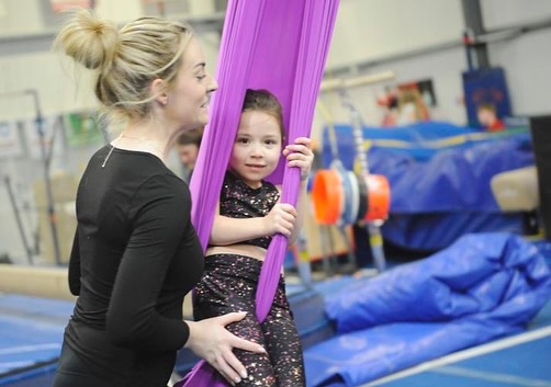 a woman holds a young girl in an acrobatic silk