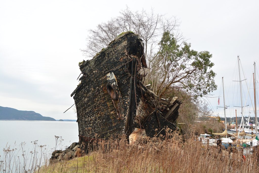 decaying wreckage of the La Merced overlooking the sea with boats in the background