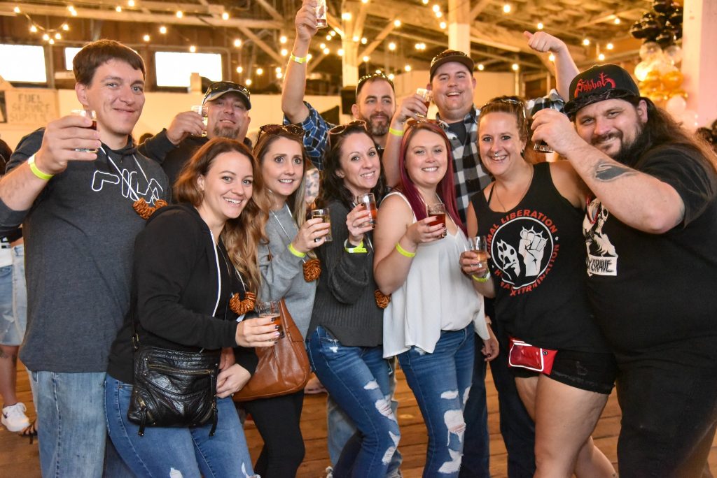 a large group of people pose for a photo with shot glasses in their hands