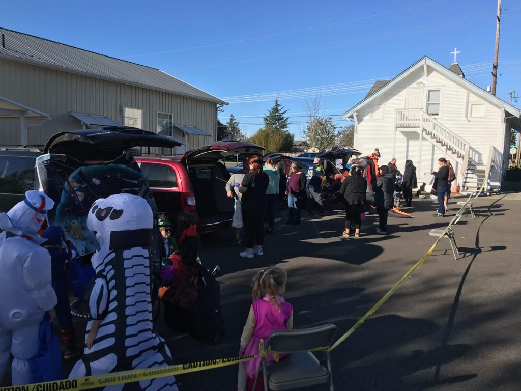 kids in costume trick or treat at car trunks in a church parking lot