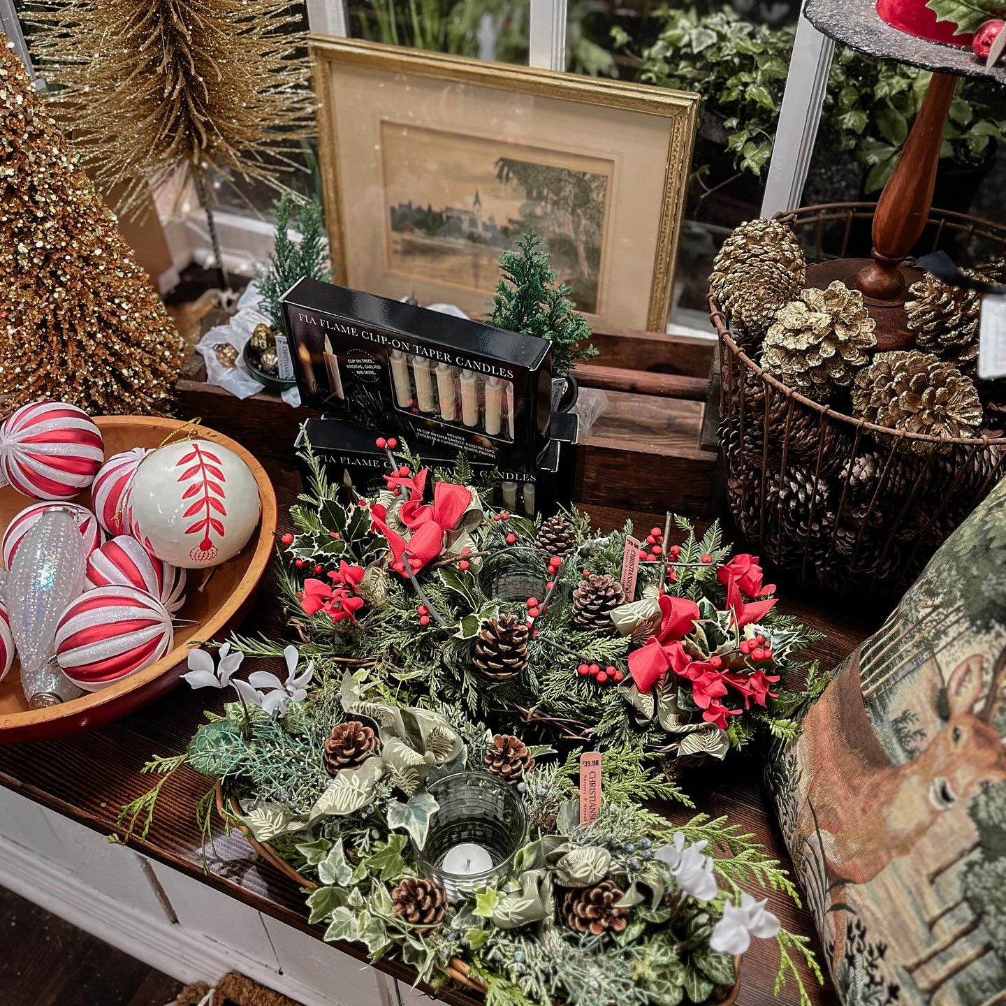 a table with greenery, red and white Christmas decorations and other items