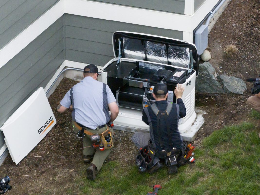 Barron Techs looking at a heat pump outside a beuilding