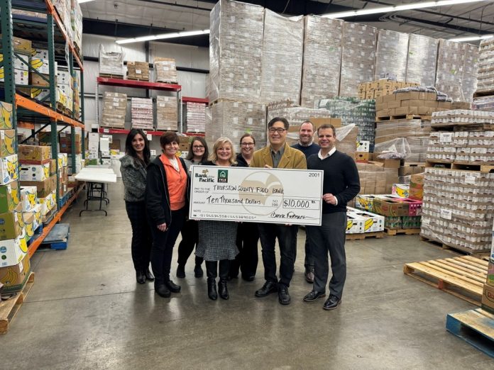 a large group of people stand around a giant check inside a warehouse