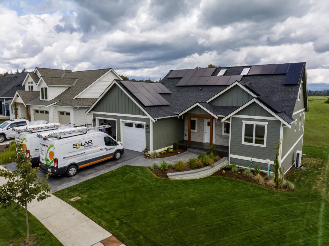 home with solar panels on the roof and a Barron Heating van in the driveway