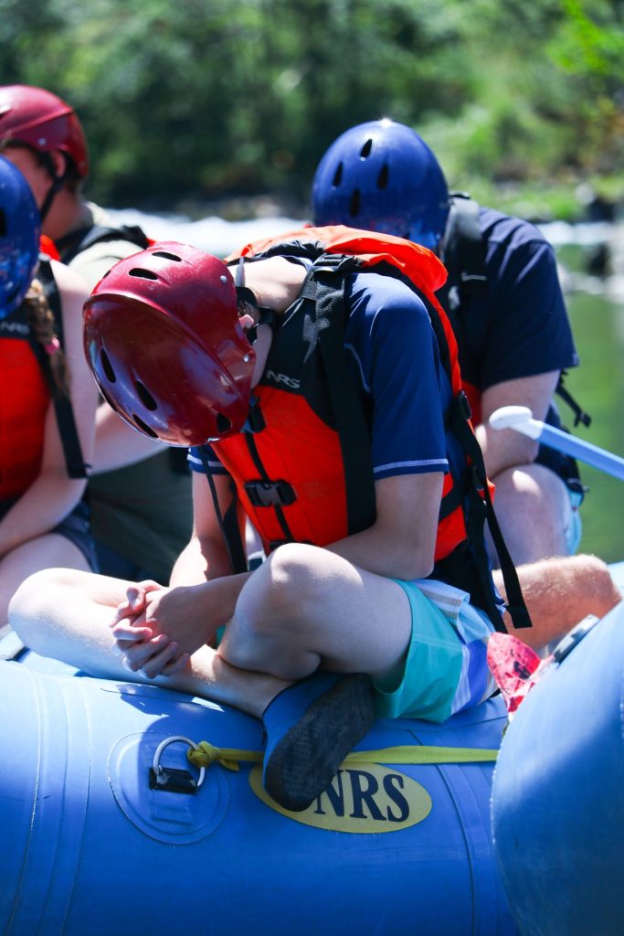 Youth sitting on a raft with their hands folded and heads bowed praying with Youth Dynamics in Anacortes