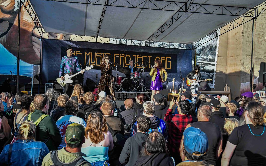 a band performs on an outdoor stage to a large crowd at the Come As You Are Music Festival