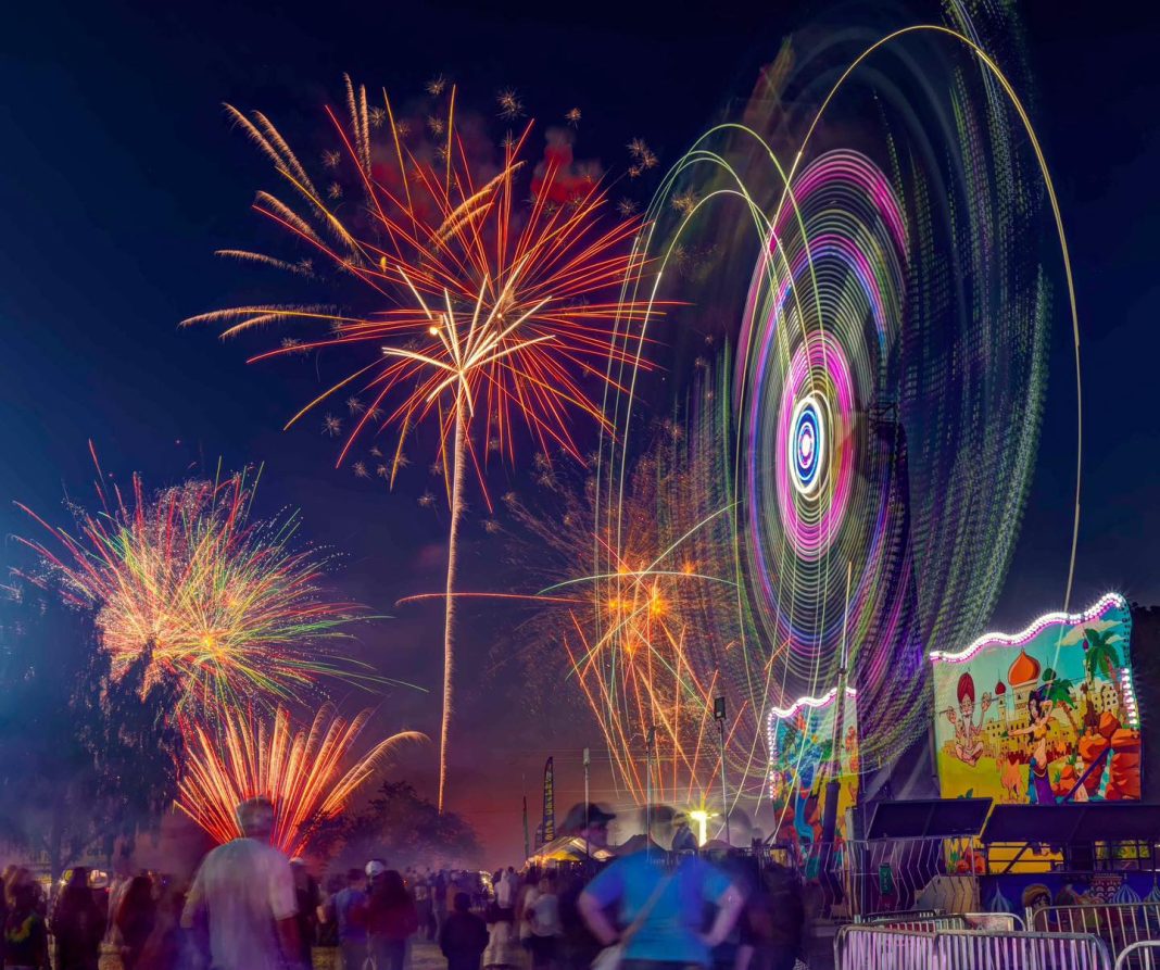 fireworks light up a night sky with a large crowd watching from below