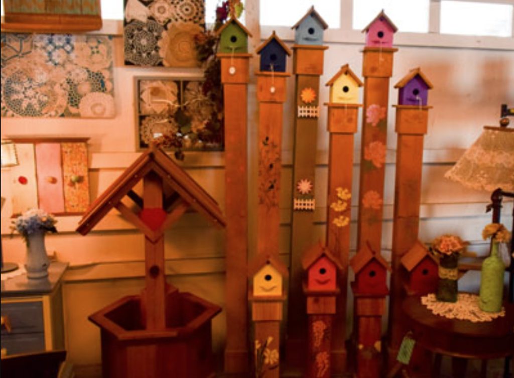 wooden house decor including a small wishing well, and fence posts with bird houses on top